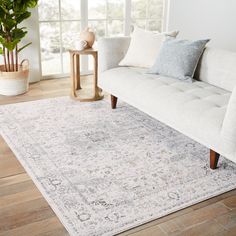 a white couch sitting on top of a wooden floor next to a plant in a living room