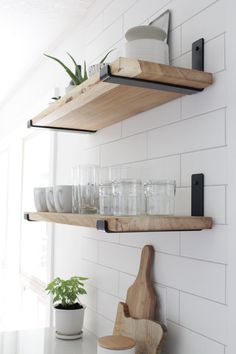 two wooden shelves filled with dishes on top of a kitchen counter next to a potted plant