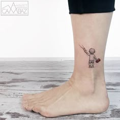 a small tattoo on the ankle of a person with a heart in his hand and an arrow