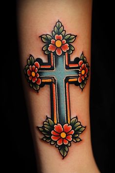 a cross with flowers and leaves on the side of her leg is shown in this tattoo design