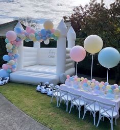 an inflatable arch with balloons and other decorations on the lawn at a birthday party