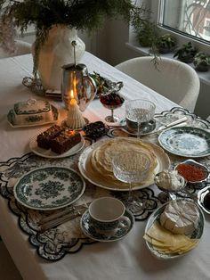 a table topped with plates and bowls filled with food next to a vase full of flowers