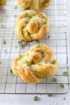 three muffins sitting on top of a cooling rack next to green onions and peas