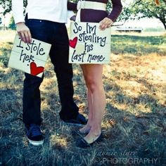 two people standing in the grass holding signs that say, i stole her last name