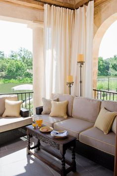 a living room filled with lots of furniture next to a window covered in white curtains