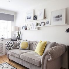 a living room filled with furniture and pictures on the wall above it's windows