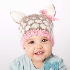 a smiling baby wearing a knitted hat with ears