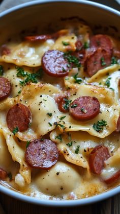 a white bowl filled with pasta and pepperoni on top of a wooden table next to a fork