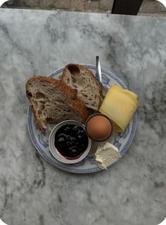 a plate with bread, butter, and an egg on it sitting on a marble table