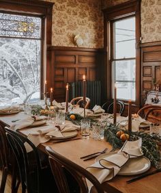 a dining room table is set with place settings and candles in front of the windows