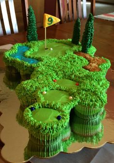 a cake shaped like a golf course with green grass and trees on the top, sitting on a table