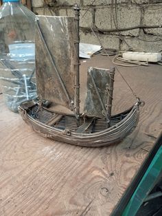 a small boat is sitting on the table next to a water bottle and some wires