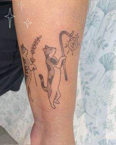 a woman with a cat tattoo on her leg holding a stick and arrow in one hand