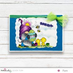 a card with an image of a gnome and chicks on it, in front of a white wooden background