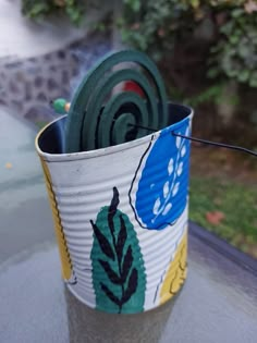 a cup with some green and blue things in it sitting on a glass table outside