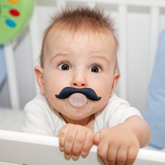 a baby with a fake moustache on his face