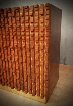 a sculpture made out of red bricks on a wooden floor next to a gray wall