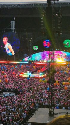 a large group of people at a concert with lights and balloons in front of them