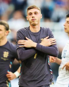 a man standing with his arms crossed in front of him and other men behind him