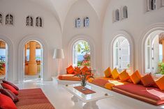 a living room filled with lots of furniture and large arched windows on the side of it