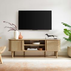 a flat screen tv mounted to the side of a wooden entertainment center in a living room