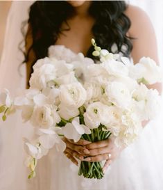 a bride holding a bouquet of white flowers