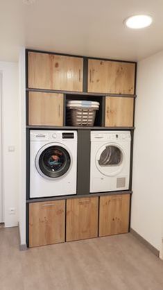 a washer and dryer in a room with wooden cabinets on the wall above them