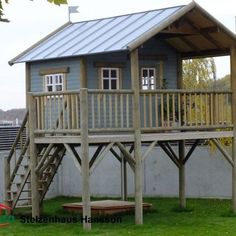 there is a small house with a deck and stairs on the grass next to it