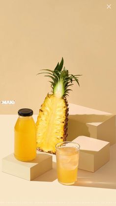 a pineapple sitting next to two jars of juice on top of a white table