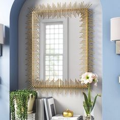 a mirror that is on the side of a wall next to a vase with flowers