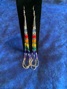 two pairs of multicolored beaded earrings sitting on top of a black stand