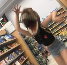 a blurry image of a woman in a store with her hands up to the ceiling