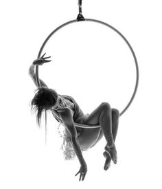 a woman is hanging upside down in the air with a hoop above her head and legs