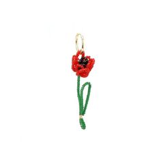 a red flower with green stems is hanging from a gold - plated hook on a white background