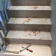 some tools are sitting on the steps in front of a set of stairs that have been stripped off