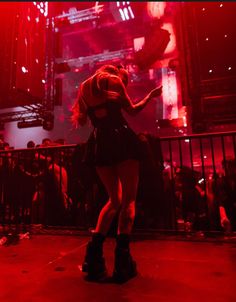 a woman standing on top of a stage in front of a crowd at a concert