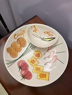 two plates with different designs on them sitting on a wooden table next to a knife and fork