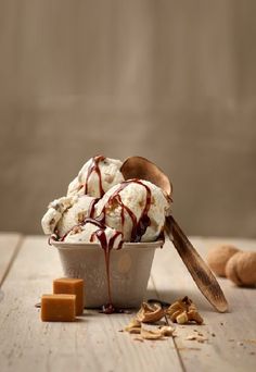 an ice cream sundae with chocolate sauce drizzled on top and nuts scattered around