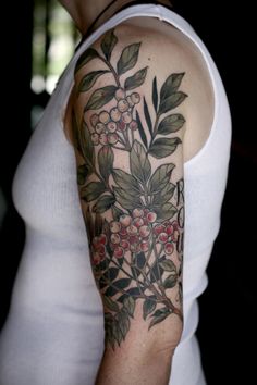 a woman's arm with flowers and leaves on it