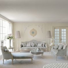 a living room filled with white furniture and lots of windows