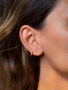 a close up of a person wearing gold ear piercings on their left side of the ear