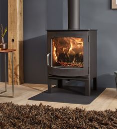 a wood burning stove in a living room next to a table and chair with a rug on the floor