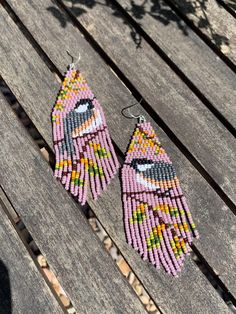 two pairs of beaded earrings sitting on top of a wooden bench