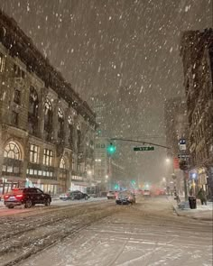 cars driving down a snowy street at night