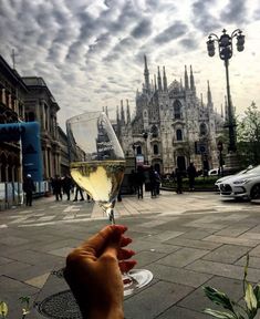 a hand holding a wine glass in front of a building