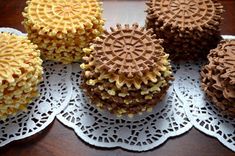 four cupcakes with chocolate frosting and sprinkles are on a doily