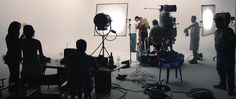 a group of people in a room with cameras and lighting equipment on the floor,