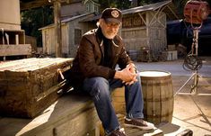 a man sitting on top of a wooden barrel