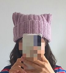 a woman taking a selfie in front of her face wearing a knitted cat hat