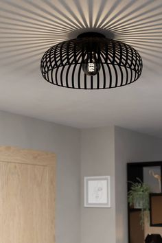 a light that is on above a bed in a room with wood floors and white walls